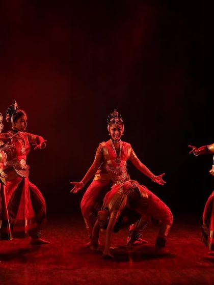 A group of dancers in a powerful formation under deep red lighting. This scene from "Shrishti Stithi Laya" evokes the intense and fiery emotions of Sati's sacrifice.