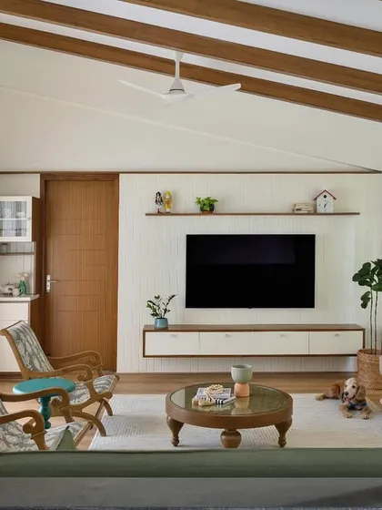 The family space in 'House of Kismish' has a true cottage charm, with a sloped roof, exposed wooden rafters, and a floating white TV unit.