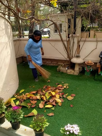 An employee sweeping fallen leaves from an artificial turf area. Even low-maintenance landscapes require regular care to look their best, and our team handles it all.