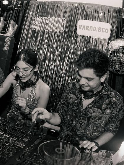 A black and white shot of me and a fellow DJ sharing a laugh behind the decks. Collaboration is key to my events, and I love sharing the console with artists I admire.