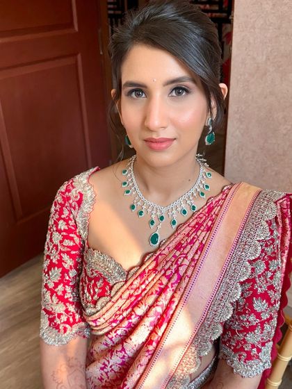 A sophisticated reception look. The makeup is clean and minimal, with a soft focus on the eyes, allowing her stunning red saree and diamond jewelry to take center stage.