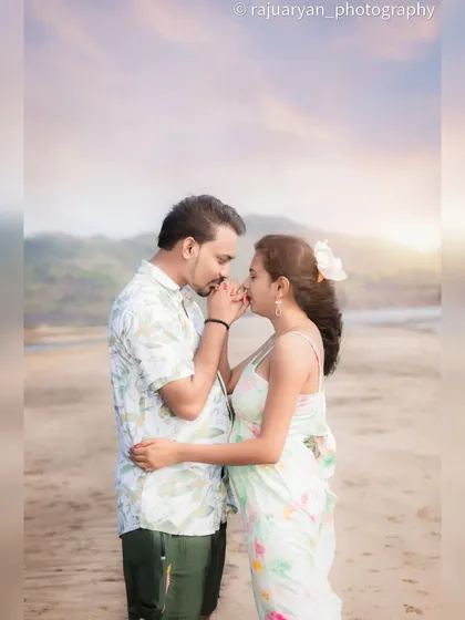 An intimate and gentle moment from a beach pre-wedding shoot. A soft kiss on the hand against the hazy, sunlit sky creates a beautifully romantic and tender portrait.