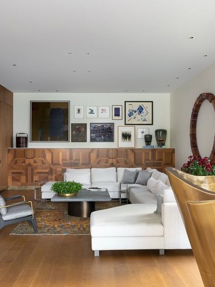 The casual lounge in the K Residence, where a large white sectional sofa offers inviting comfort. The space is anchored by a high marquetry unit from our Koko collection, above which hangs a curated gallery of master artists, blending high art with everyday living.