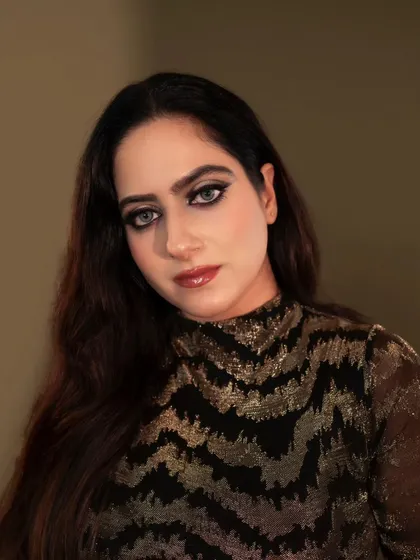 A bold and dramatic close-up portrait. The dark, smoky eye makeup and intense gaze are captured with precise lighting that adds to the moodiness of the shot.