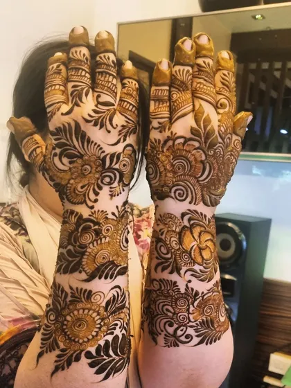 A stunning, bold floral design that covers the hands and wrists. The dark shading makes the flowers and leaves stand out dramatically.