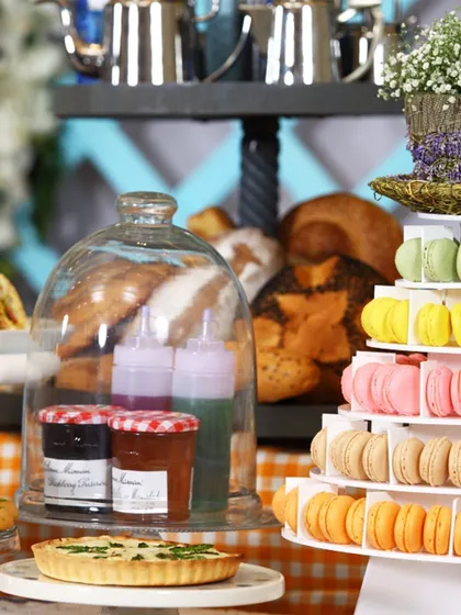 A lavish high-tea setup featuring a multi-tiered macaron tower, fresh pastries, and jars of jam. This demonstrates our ability to create elaborate and visually enthralling dessert and snack displays.