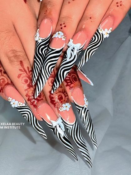 A full view of the fierce zebra-inspired stiletto nails, complete with delicate white 3D bows and rhinestone accents.