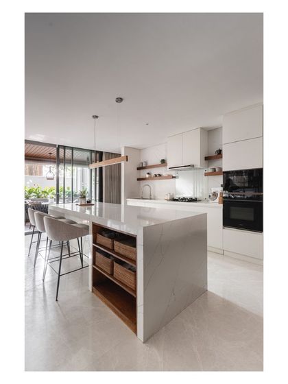 The kitchen island provides ample workspace and storage, with integrated wooden baskets for easy access to everyday items.