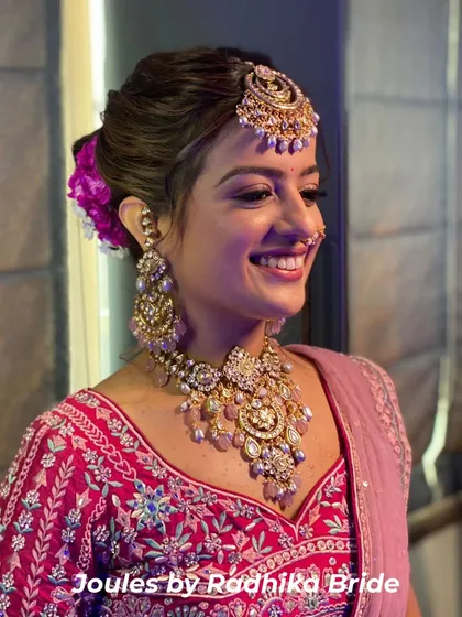 A smile that says it all. Our radiant bride shines in a complete bridal set, featuring a layered polki necklace with pastel bead drops, matching earrings, and an ornate maang tikka for her special day.