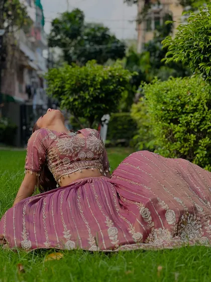 A beautiful shot of a model lounging in our mauve pleated lehenga. The silver embroidery adds a touch of sparkle.