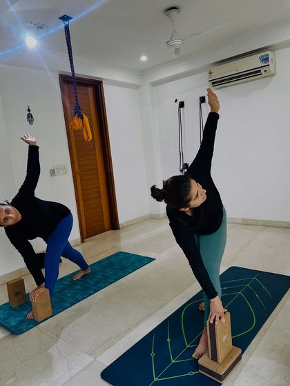 Students use blocks to support their hands in Trikonasana (Triangle Pose). This simple adjustment helps to keep the chest open and the spine long, ensuring they get the full benefit of the twist.