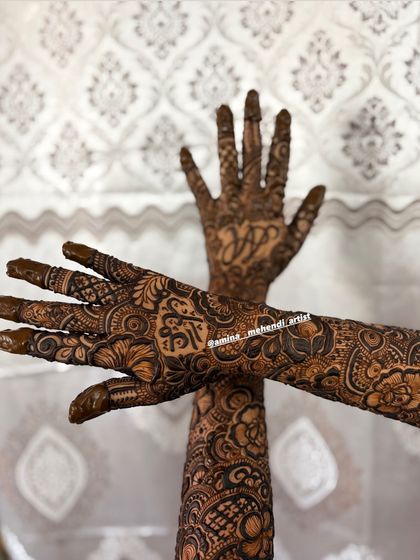 A creative pose showing the personalized mehendi, with initials 'J' and 'A' and a name in Arabic script.