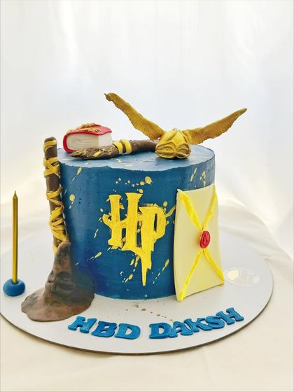 A magical Harry Potter cake featuring a hand-sculpted sorting hat, broomstick, and golden snitch.