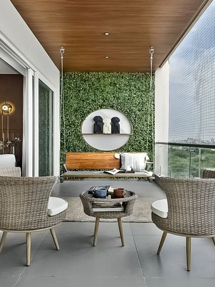 An elegant balcony design featuring a comfortable swing, wicker armchairs, and a vertical garden as a backdrop. The space overlooks the city, offering a perfect blend of urban views and natural comfort.