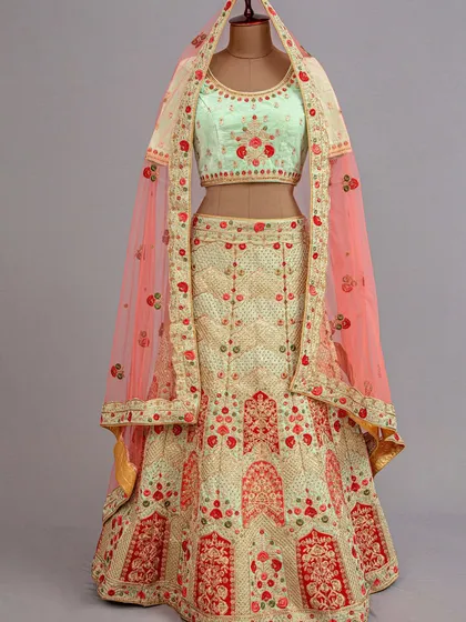 A detailed look at one of our designer bridal lehengas on a mannequin. This mint green and peach lehenga features heavy, multi-colored embroidery, making it a premium rental option for a wedding reception.