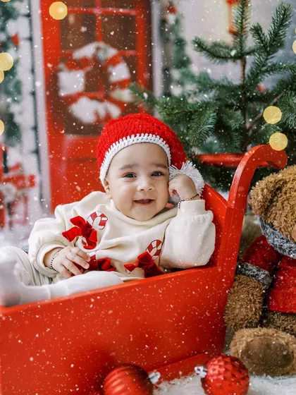 A happy smile from the same little girl in her festive sleigh, enjoying the Christmas magic.