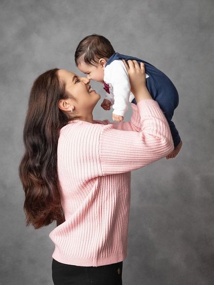 A mother shares a sweet nose-to-nose moment with her baby. Lifting him up high brings out the most beautiful, natural smiles.