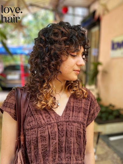 A side profile of the curly shag cut with highlights. The colour on the ends emphasizes the modern, edgy shape of the cut.