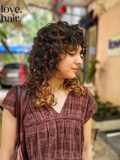A side profile of this stunning curly shag. The layers and fringe are cut to enhance the natural curl pattern and create a beautiful shape.