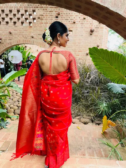 A bride in a stunning red banarasi saree, with a matching blouse featuring a tie-up keyhole back.