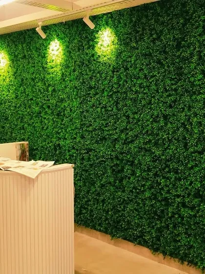 We transformed this office reception area with a floor-to-ceiling artificial green wall. The track lighting highlights the texture of the foliage, creating a professional and refreshing first impression for visitors.