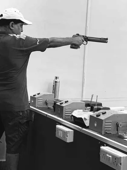 A black and white shot of me, Vikram Singh, demonstrating the classic one-handed stance for 10m air pistol shooting. Leading by example is a core part of my coaching philosophy.