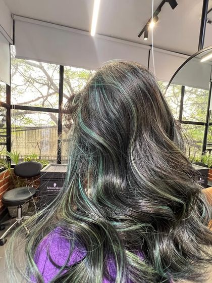 For a truly unique look, I added flashes of green to this client's dark hair. It's an artistic and edgy way to express personal style.