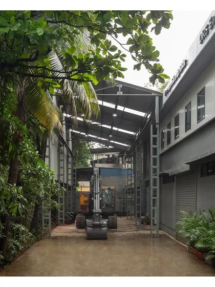 The covered breezeway designed for the movement of heavy machinery between the workshop and outdoor areas. The tall steel structure and translucent roofing create a functional and well-lit transitional space.