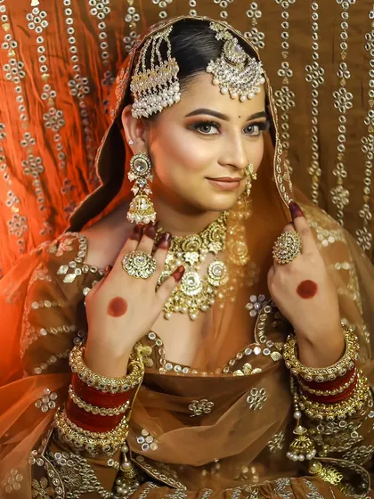A happy bride showing off her complete look, including the traditional red chooda bangles. The makeup is radiant and joyful, perfect for the occasion.