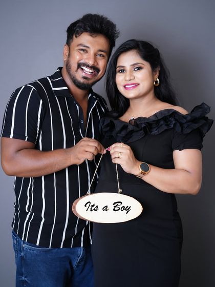 A joyful couple holding a sign that says "It's a Boy" during their studio maternity session. Their happiness is absolutely contagious in this shot.