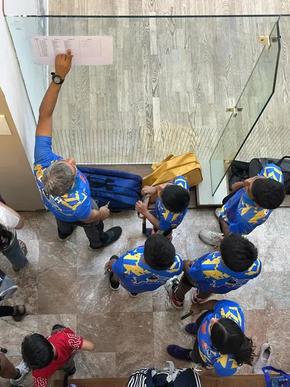 A bird's-eye view of a coaching moment. I'm explaining the match draw to our junior players before our community event begins.