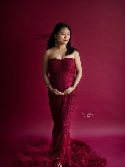 A beautiful solo portrait against a rich, solid-colored backdrop. The wind in her hair adds a touch of movement and life to this stunning studio shot.