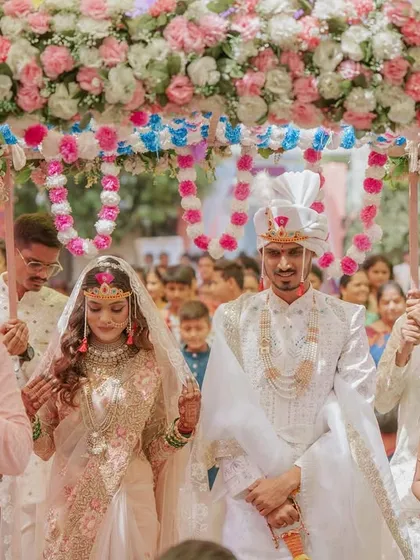 The bride and groom making their entrance under a beautiful floral canopy, a key moment in the wedding ceremony.
