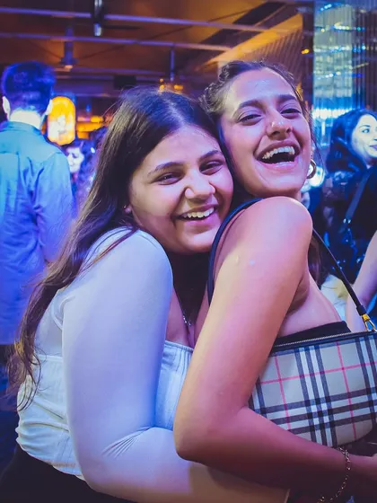 Two friends hugging and laughing on the dance floor. Capturing the joy of a great night out.