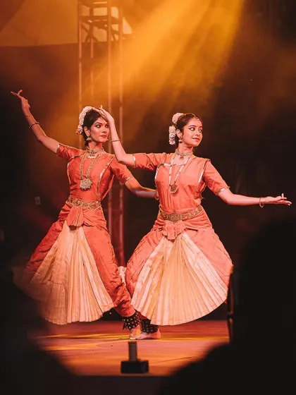 Two classical dancers perform in perfect unison, their forms illuminated by a warm spotlight. This image highlights the symmetry and grace of their art form.