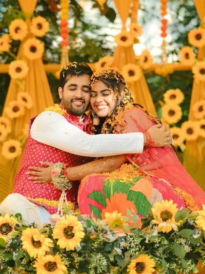 A warm hug at the end of a joyful Haldi ceremony. The couple is covered in flowers and happiness.