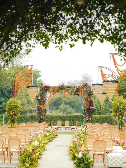 A view of the wedding aisle through a natural arch of green leaves. This perspective highlights the journey to the mandap, creating a sense of anticipation and natural beauty.