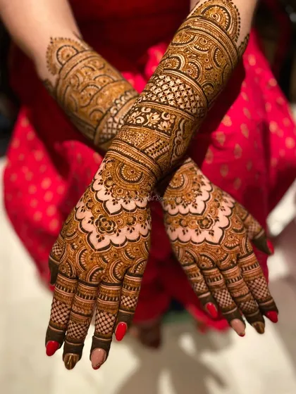 This back-of-hand design features a mix of traditional motifs and modern patterns. The red nail polish provides a beautiful contrast to the dark henna.