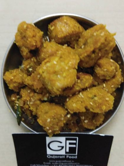 A bowl of crispy fried Muthiya, seasoned with sesame seeds. These savory dumplings are made from gram flour and spices, making for a perfect tea-time snack.