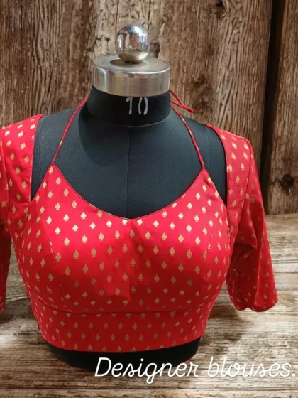 This red brocade blouse with a modern halter cut and sleeves is designed to turn heads. You can get this style customized to suit you perfectly.