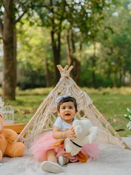 Capturing the little interactions, like this birthday girl reaching for her stuffed dog, adds a layer of personality and sweetness to milestone photos.