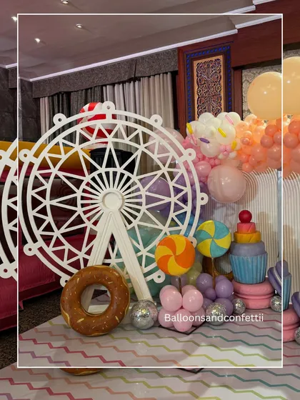 Detail shot of the custom-made props, including a large ferris wheel, lollipops, and a giant donut, which make the theme so immersive.