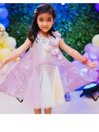 A happy client wearing her purple "Pari" dress. The iridescent sequins and pastel tulle panels catch the light beautifully as she moves.