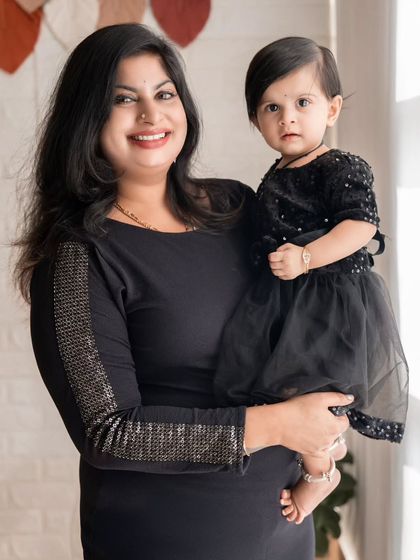 A classic portrait of a mother holding her daughter, both looking elegant in black.
