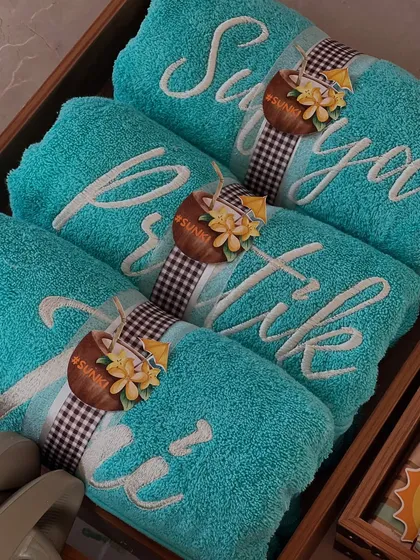 Soft, fluffy towels personalized with embroidered names for a beach-themed bachelorette party. The turquoise color and custom tags with the wedding hashtag perfectly matched the sun and sand vibe.
