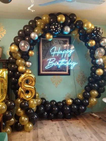 A glamorous 18th birthday party with a black, gold, and silver theme. The circular balloon arch and foil number balloons create a sophisticated backdrop for this milestone celebration.