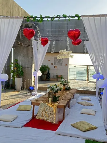 The rooftop setup during the day, showing how the white drapes and red heart balloons create a festive and romantic vibe against the city skyline.