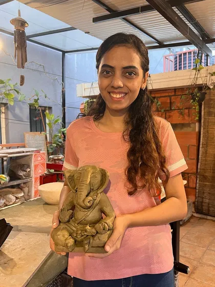 A proud student holding her finished Ganesha idol. The smile on her face says it all.