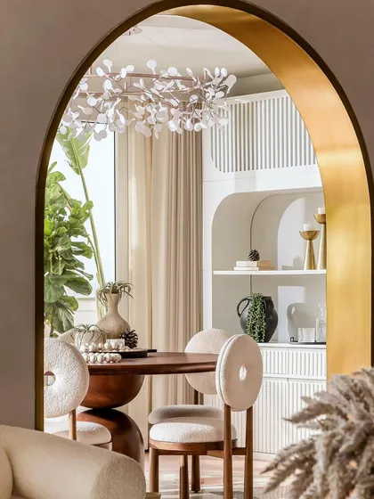 A view of the dining area through a brass-lined arch, with a dainty chandelier that lights up like fireflies in the evening.