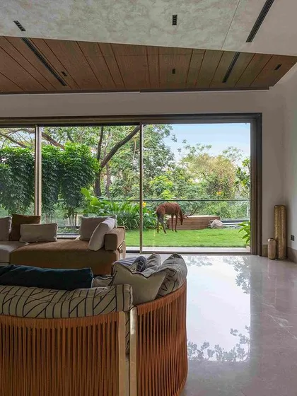A spacious living room with floor-to-ceiling windows offering an uninterrupted view of the garden. The interior design is kept minimal to ensure the landscape remains the focal point of the home.
